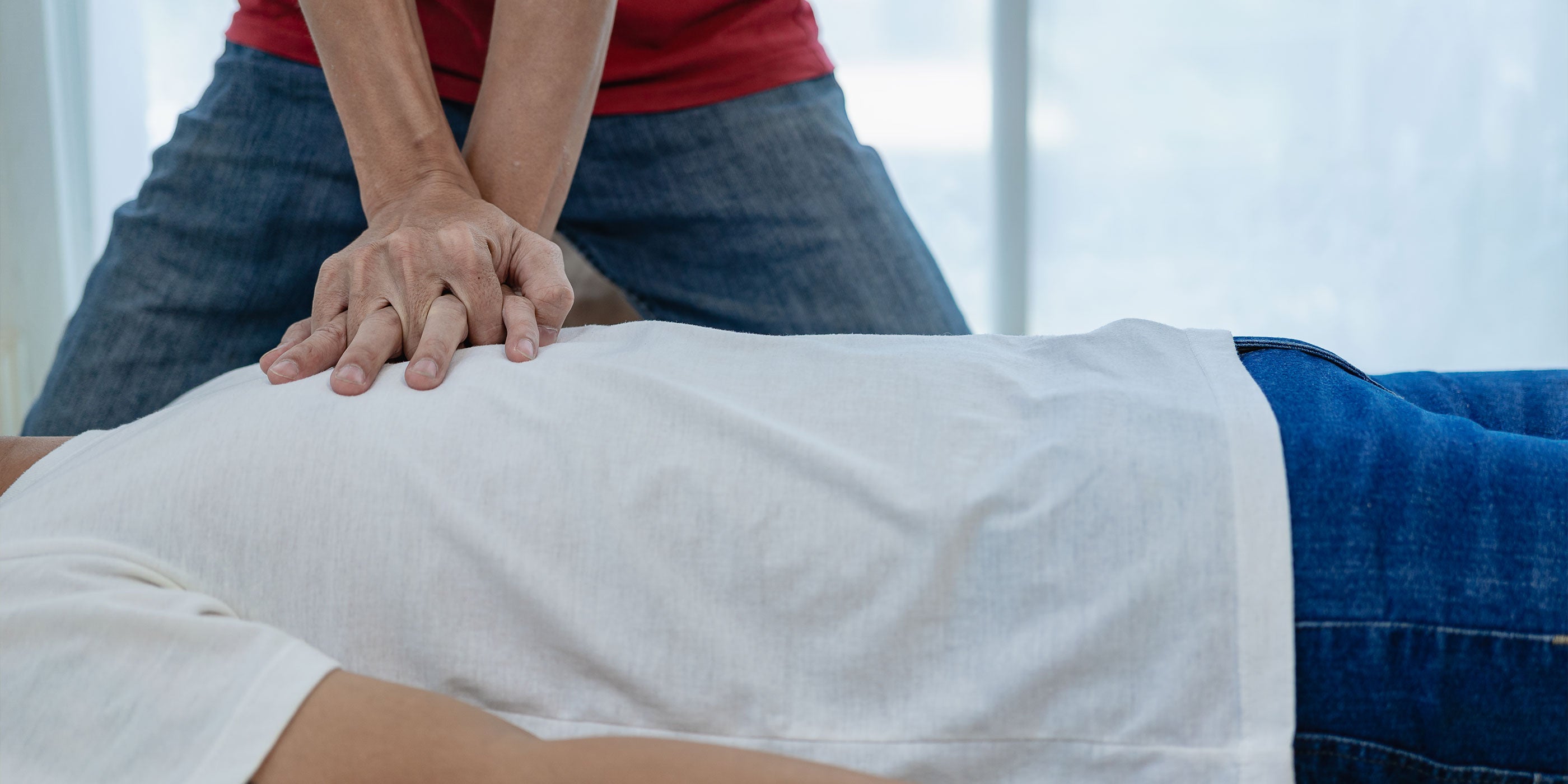 A close up of a man performing CPR on another man